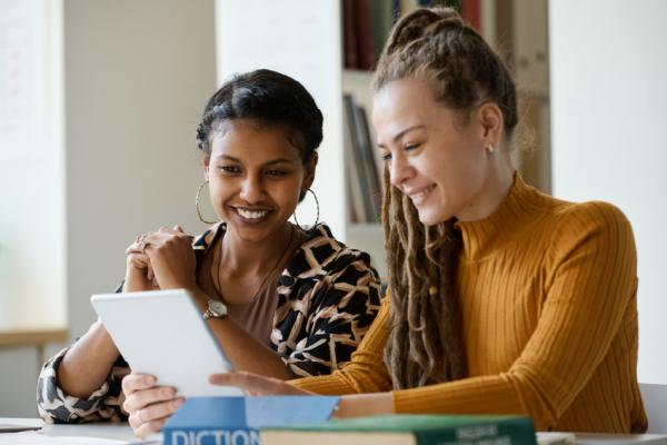 Two women are working together on a desk in an office space.